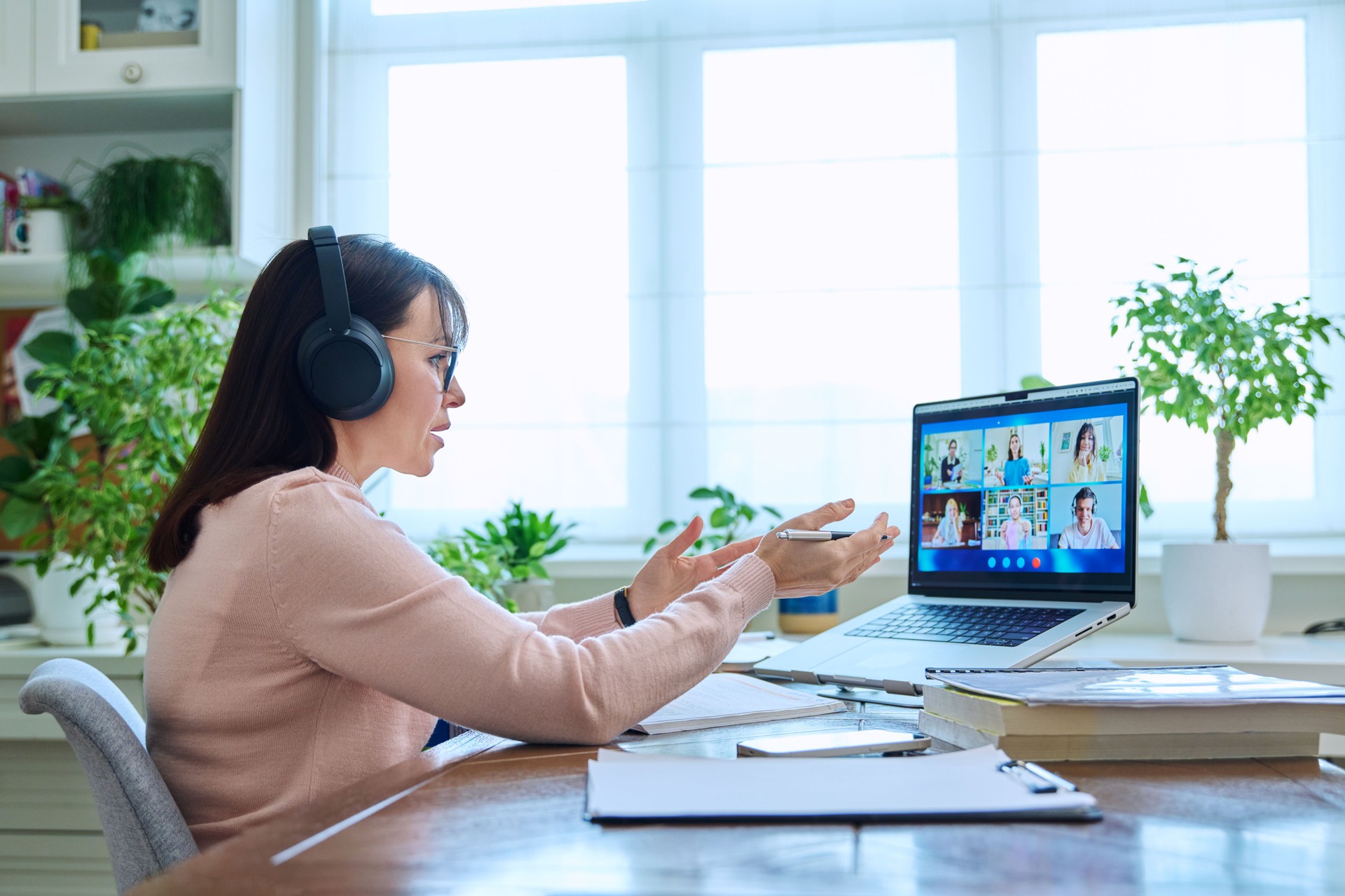 Woman teacher in headphones teaching online, high school students on computer screen