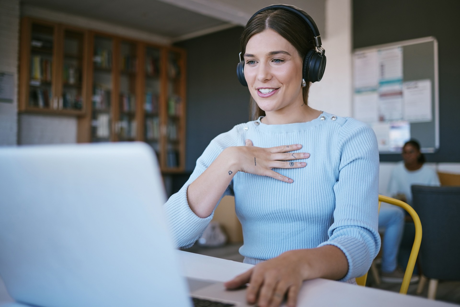 Video call, presentation and student with laptop and headphones talking in virtual class discussion at university library or workspace. College woman teacher in virtual zoom call for elearning course